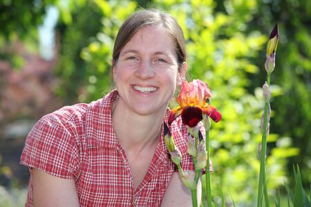 Smiling woman with iris flower in the gardenの写真素材