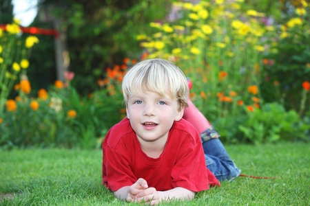 Smiling young boy lying on grass in the gardenの写真素材