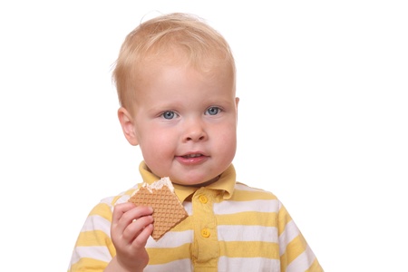 Portrait of a young kid eating cookies on white backgroundの写真素材
