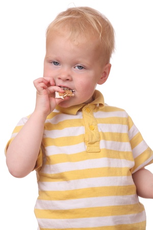 Portrait of a young kid eating cookies on white backgroundの写真素材