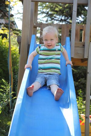 Cute young kid playing on a slideの写真素材