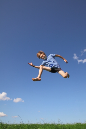 Happy young boy jumping in the meadowの写真素材