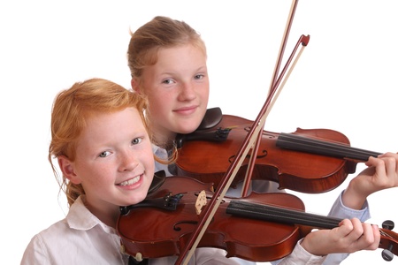 Two young girls playing violin on white backgroundの写真素材