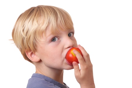 Portrait of a young boy eating a tomatoの写真素材
