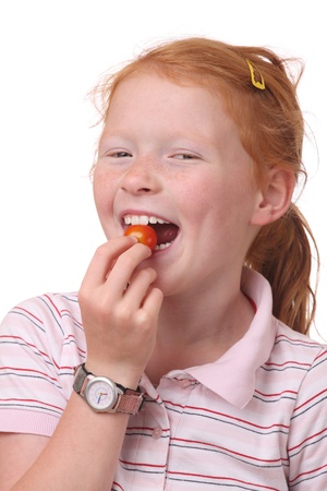 Portrait of a young girl eating a tomatoの写真素材