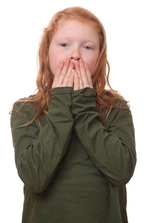 Young red haired girl covers her mouth on white backgroundの写真素材