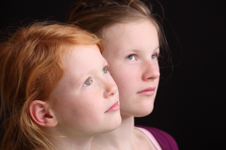 Portrait of two cute looking girls on black backgroundの写真素材