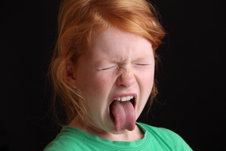 Portrait of an angry young girl sticking out her tongueの写真素材