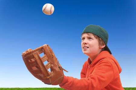 Young boy tries to catch a baseballの写真素材