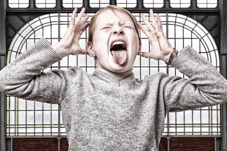 Young screaming girl in front of an old windowの写真素材