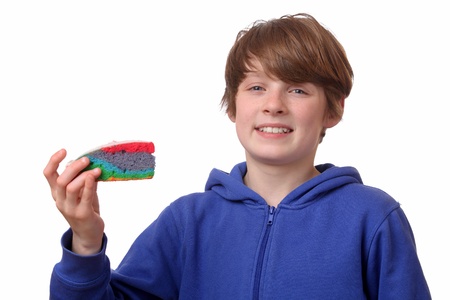 Teenage boy eating a piece of colorful cake on white backgroundの写真素材