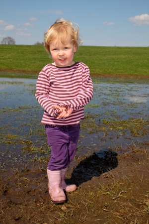 Happy toddler having fun in a muddy puddleの写真素材