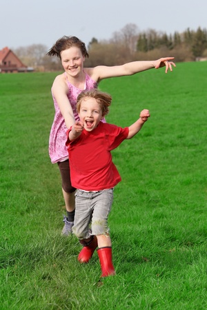 Two happy kids running on a green meadowの写真素材