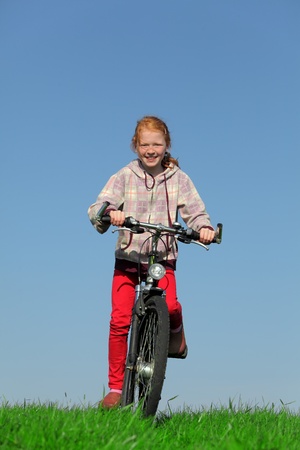 Happy young girl on bike on green meadowの写真素材