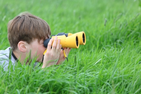 Young boy in a meadow looking through binoculars の写真素材