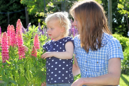 Mother and daughter enjoy some flowers in the gardenの写真素材