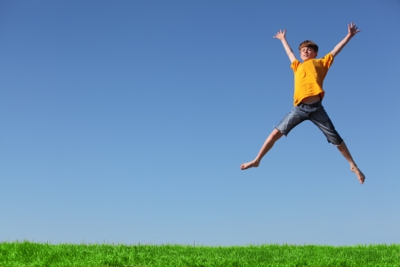 Happy young boy jumping in the meadowの写真素材