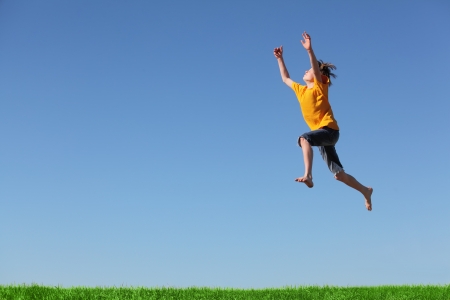 Happy young boy jumping in the meadowの写真素材