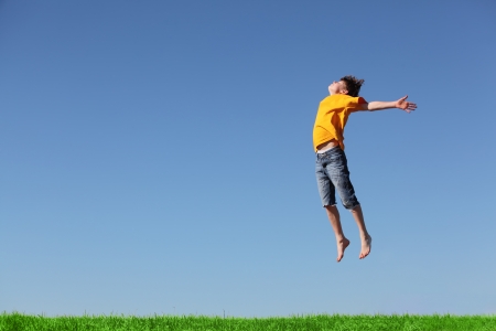 Happy young boy jumping in the meadowの写真素材
