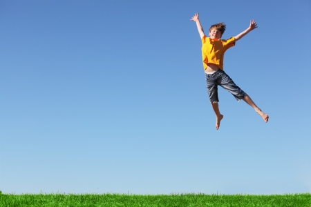 Happy young boy jumping in the meadowの写真素材
