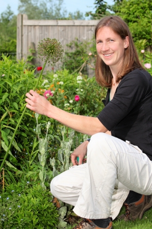 Happy young woman in the garden holding a flowerの写真素材