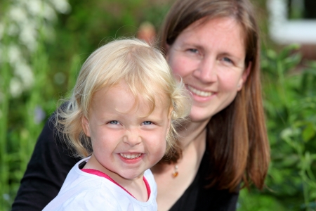 Smiling mother with daughter outside in the gardenの写真素材