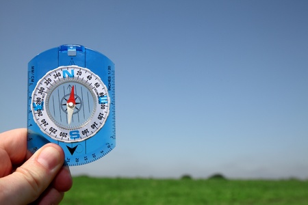Male hand holding a compass over a nature background 