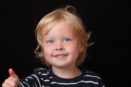 Portrait of a smiling toddler with thumbs upの写真素材