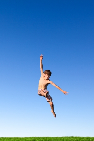 Happy young boy jumping in the meadow の写真素材