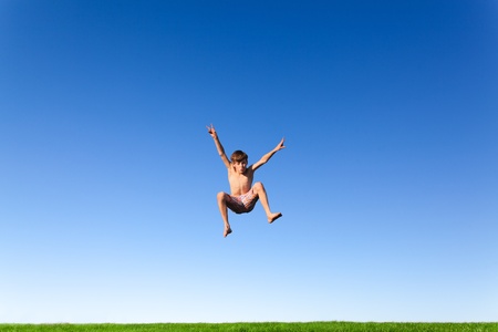 Happy young boy jumping in the meadow の写真素材