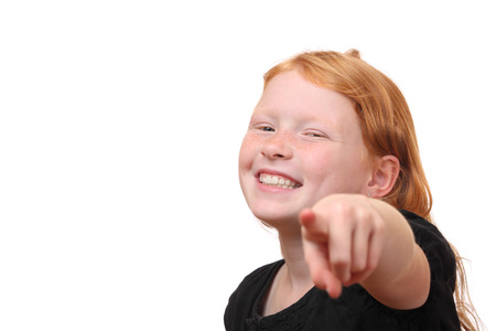 Happy young girl points to camera on white backgroundの写真素材