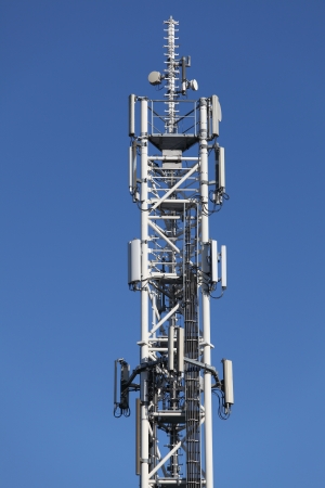 Telecommunication tower with antennas on blue skyの写真素材