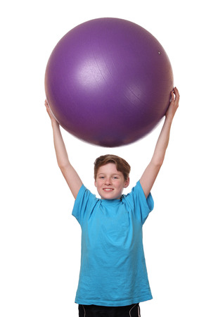 Young boy holding big pilates ball on his head on white backgroundの写真素材