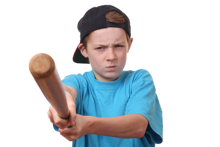 Portrait of an angry young boy holding a baseball bat on white backgroundの写真素材