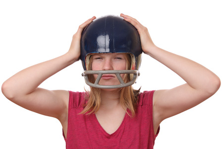 Portrait on an angry teenage girl wearing a football helmet on white backgroundの写真素材