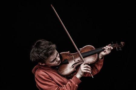 Young boy plays violin on black の写真素材