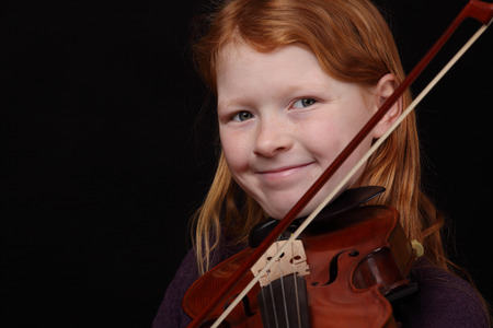Young girl plays violin on black の写真素材