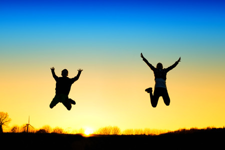 Active kids jump in meadow at sunsetの写真素材