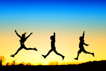 Active kids jump in meadow at sunsetの写真素材