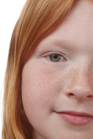 Young red-haired girl with freckles on white backgroundの写真素材
