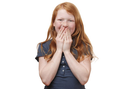 Portrait of a surprised young girl covering her mouth with handsの写真素材