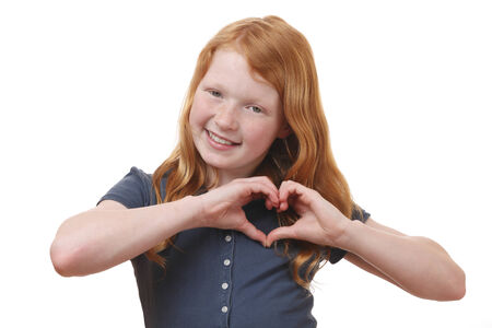 Portrait of a young girl showing heart shape with hands on white backgroundの写真素材