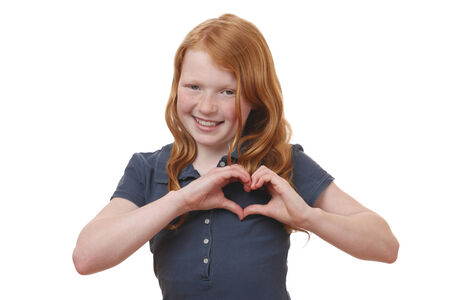 Portrait of a young girl showing heart shape with hands on white backgroundの写真素材