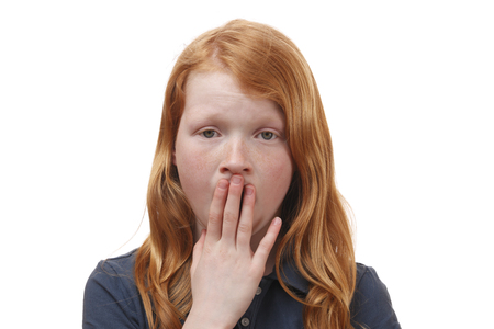 Portrait of a surprised young girl covering her mouth with handsの写真素材