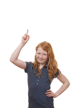 Portrait of a young girl pointing up on white backgroundの写真素材
