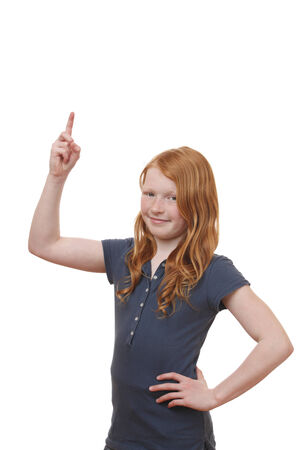 Portrait of a young girl pointing up on white backgroundの写真素材