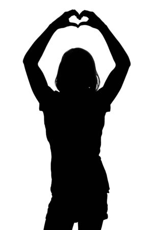 Silhouette of a young girl showing heart shape with hands on white backgroundの写真素材
