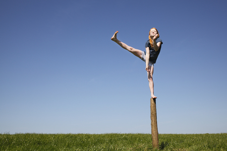 Young girl balancing outdoors on a trunk of a treeの写真素材