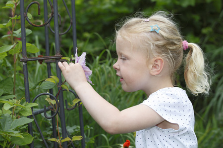 Adorable young girl enjoys some flowers in the gardenの写真素材