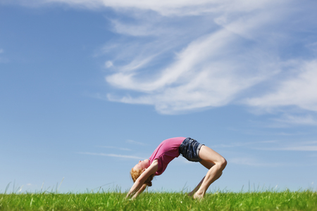 Young girl doing a back arch in a meadowの写真素材